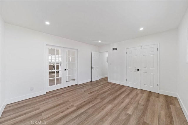 empty room with light hardwood / wood-style floors and french doors