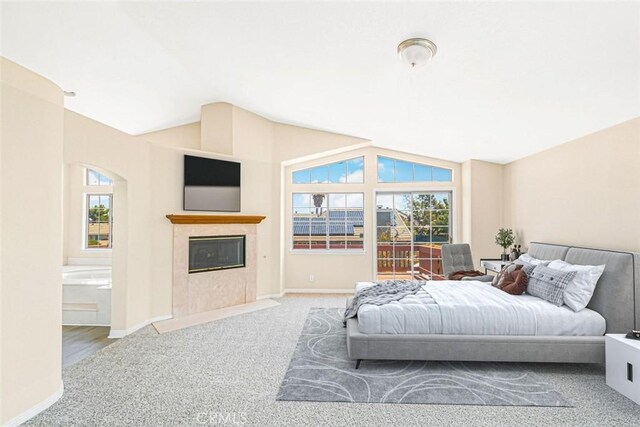 carpeted bedroom featuring vaulted ceiling, ensuite bath, and multiple windows