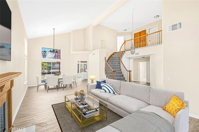 living room featuring beam ceiling, light hardwood / wood-style flooring, and high vaulted ceiling