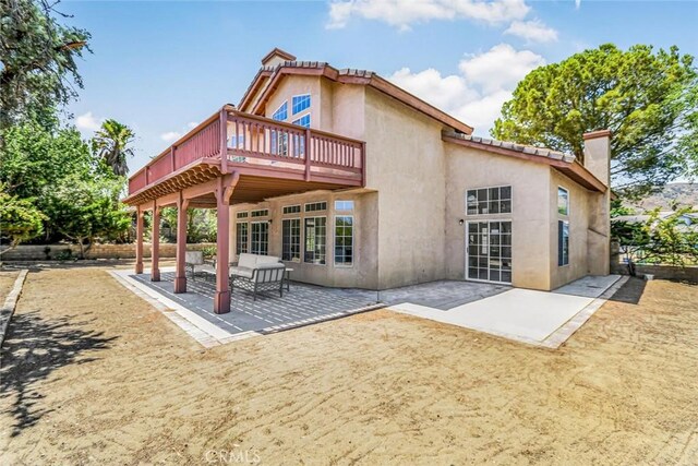 rear view of property featuring a wooden deck and a patio