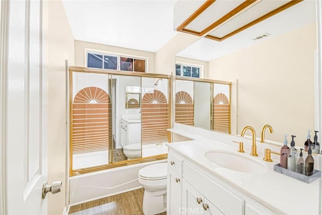 full bathroom with combined bath / shower with glass door, vanity, toilet, and hardwood / wood-style flooring