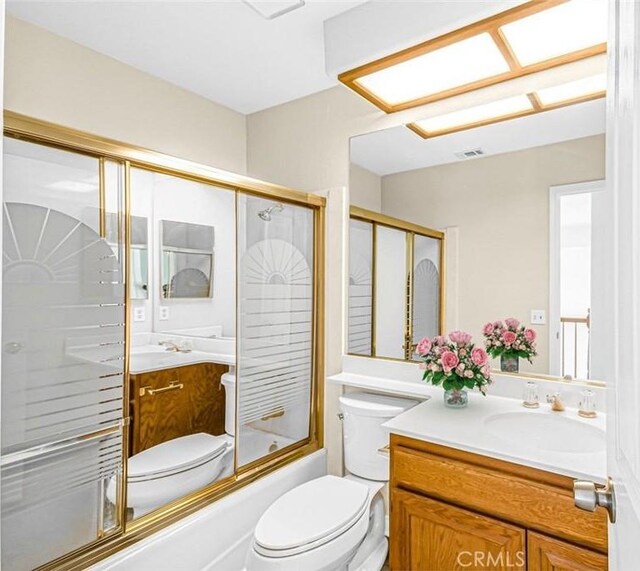 full bathroom featuring toilet, vanity, and shower / bath combination with glass door