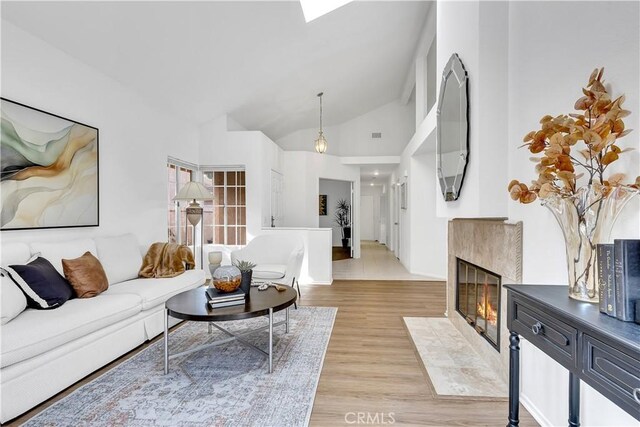 living room featuring vaulted ceiling, a high end fireplace, and light hardwood / wood-style floors