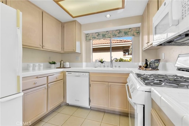 kitchen with sink, white appliances, light tile patterned floors, and tile counters