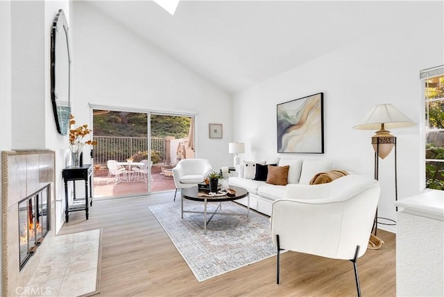 living room with a fireplace, light hardwood / wood-style flooring, and high vaulted ceiling