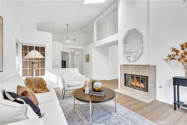 living room featuring high vaulted ceiling, hardwood / wood-style floors, and a tile fireplace