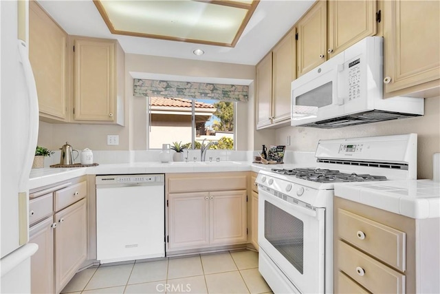 kitchen with light tile patterned flooring, sink, tile countertops, and white appliances