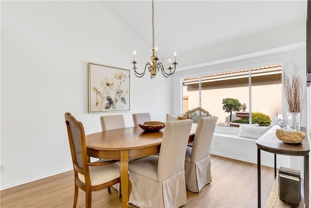 dining room with light wood-type flooring, lofted ceiling, and a notable chandelier