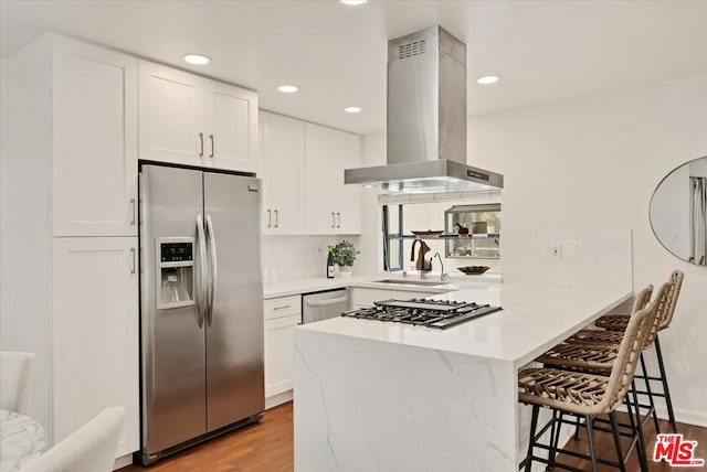 kitchen featuring white cabinets, extractor fan, stainless steel appliances, sink, and kitchen peninsula