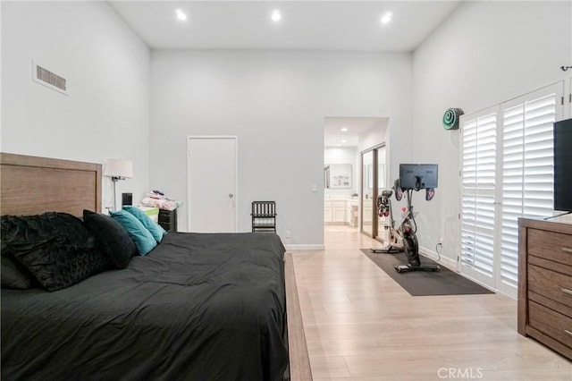 bedroom featuring light hardwood / wood-style floors and a high ceiling