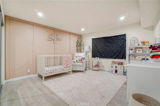 bedroom featuring light wood-type flooring and a crib