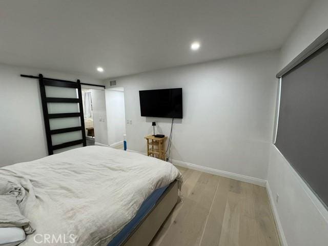 bedroom with light wood-type flooring and a barn door