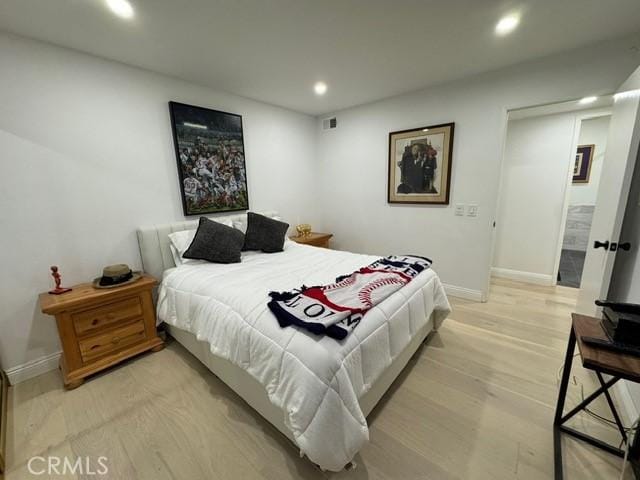 bedroom with connected bathroom and light hardwood / wood-style flooring