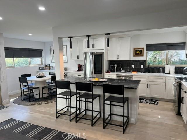 kitchen with a kitchen bar, white cabinets, appliances with stainless steel finishes, and a center island