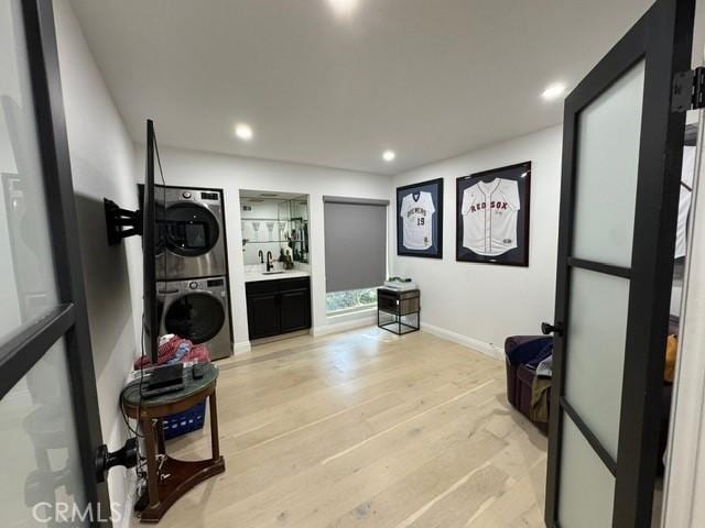 interior space featuring sink, stacked washer and clothes dryer, and light hardwood / wood-style floors