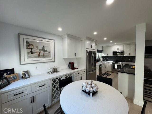 kitchen featuring decorative backsplash, stainless steel appliances, and white cabinetry