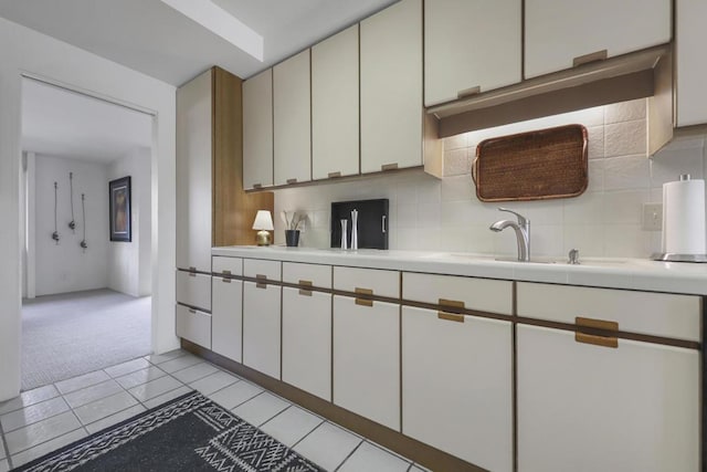 kitchen featuring light carpet, white cabinets, decorative backsplash, and sink