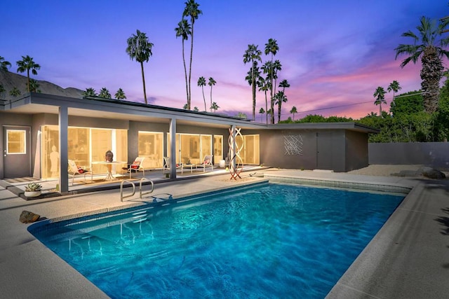 pool at dusk featuring a patio