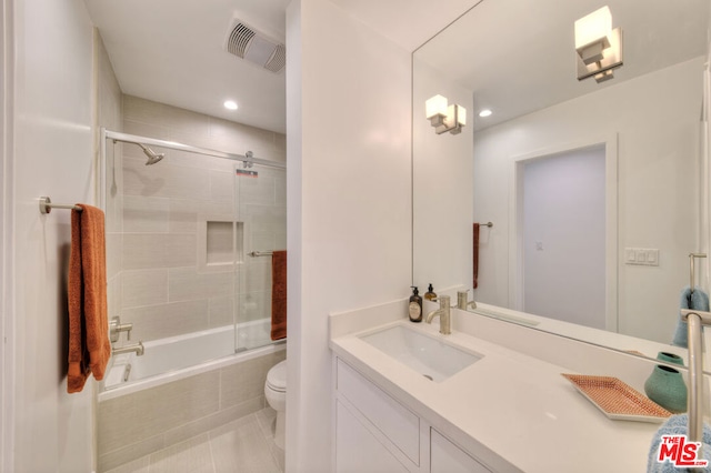 full bathroom with toilet, bath / shower combo with glass door, tile patterned flooring, and vanity