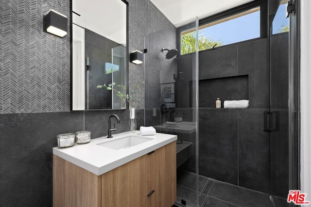 bathroom featuring a shower with shower door, vanity, tile walls, and decorative backsplash