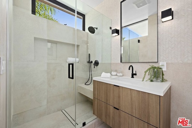 bathroom featuring a shower with door, vanity, and tile walls