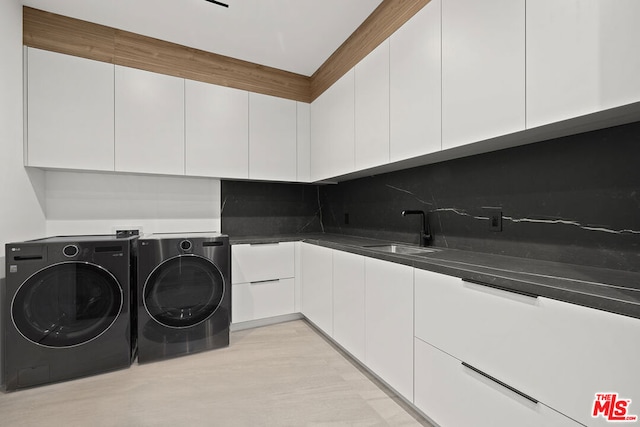 laundry area with cabinets, washer and clothes dryer, and sink