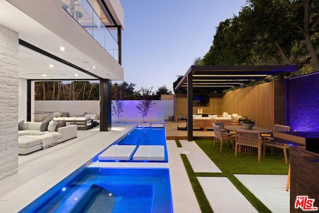 pool at dusk featuring an in ground hot tub, an outdoor hangout area, and a patio