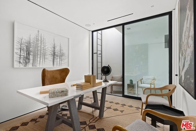 office area with floor to ceiling windows and light hardwood / wood-style flooring