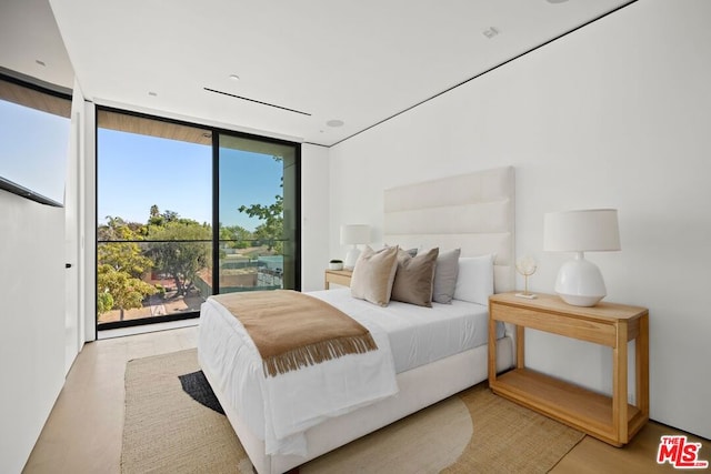 bedroom with a wall of windows, light hardwood / wood-style floors, and multiple windows