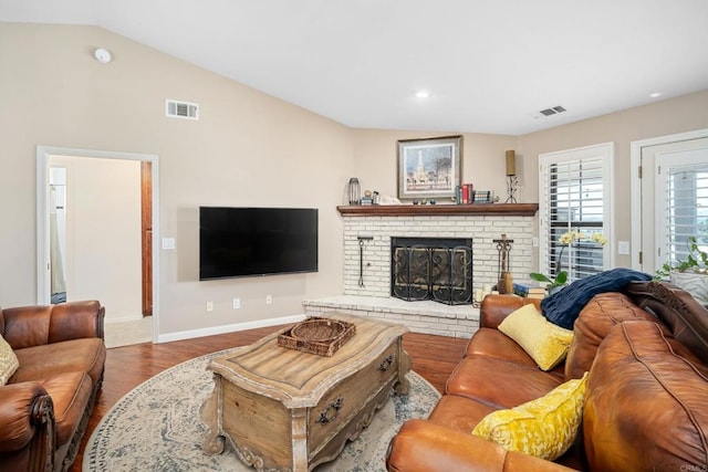 living room featuring a brick fireplace, hardwood / wood-style floors, and lofted ceiling