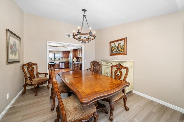 dining room with light hardwood / wood-style floors and a notable chandelier