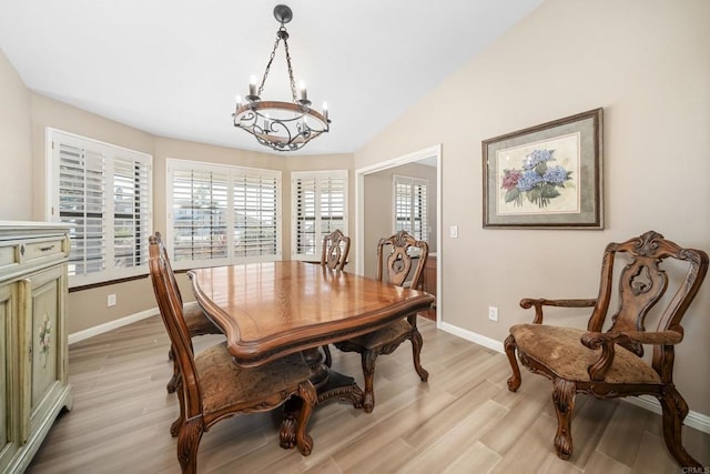 dining space featuring vaulted ceiling, a chandelier, and light hardwood / wood-style floors