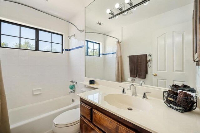 full bathroom with toilet, a healthy amount of sunlight, vanity, and shower / bathtub combination with curtain