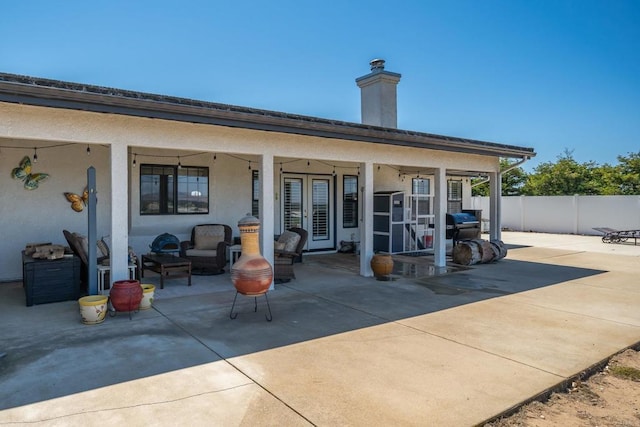 rear view of property with french doors, a patio area, and outdoor lounge area