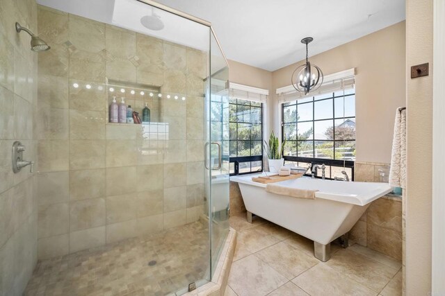 bathroom with tile patterned flooring, an inviting chandelier, and shower with separate bathtub