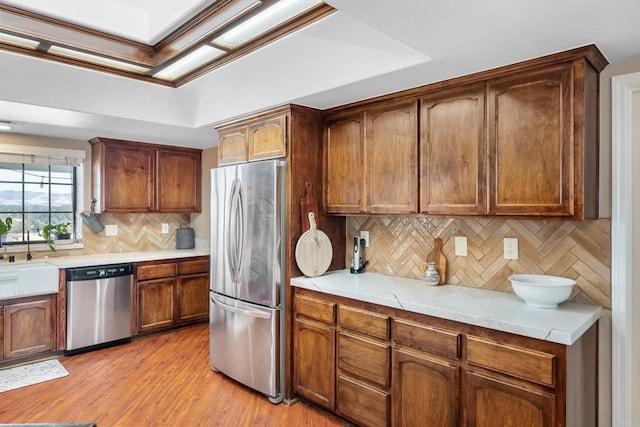 kitchen with sink, backsplash, stainless steel appliances, and light wood-type flooring