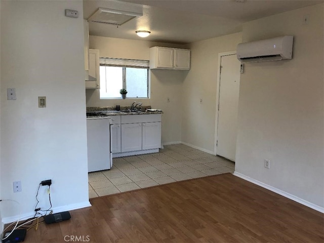 kitchen featuring white cabinetry, light wood-type flooring, stove, an AC wall unit, and sink