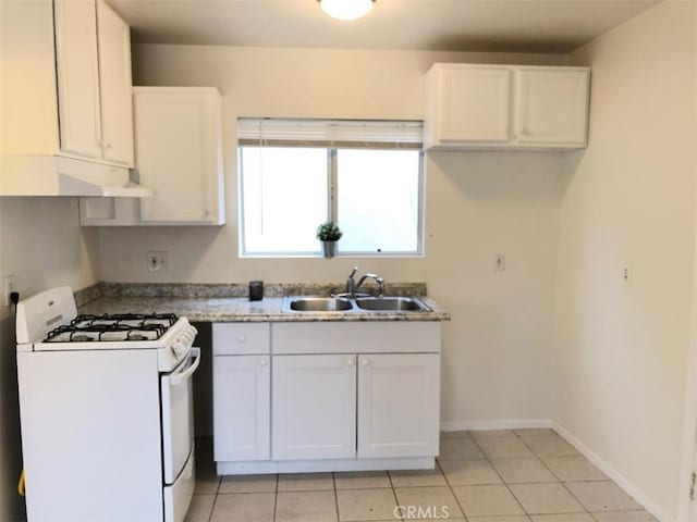 kitchen with light tile patterned floors, sink, white cabinetry, and white gas stove