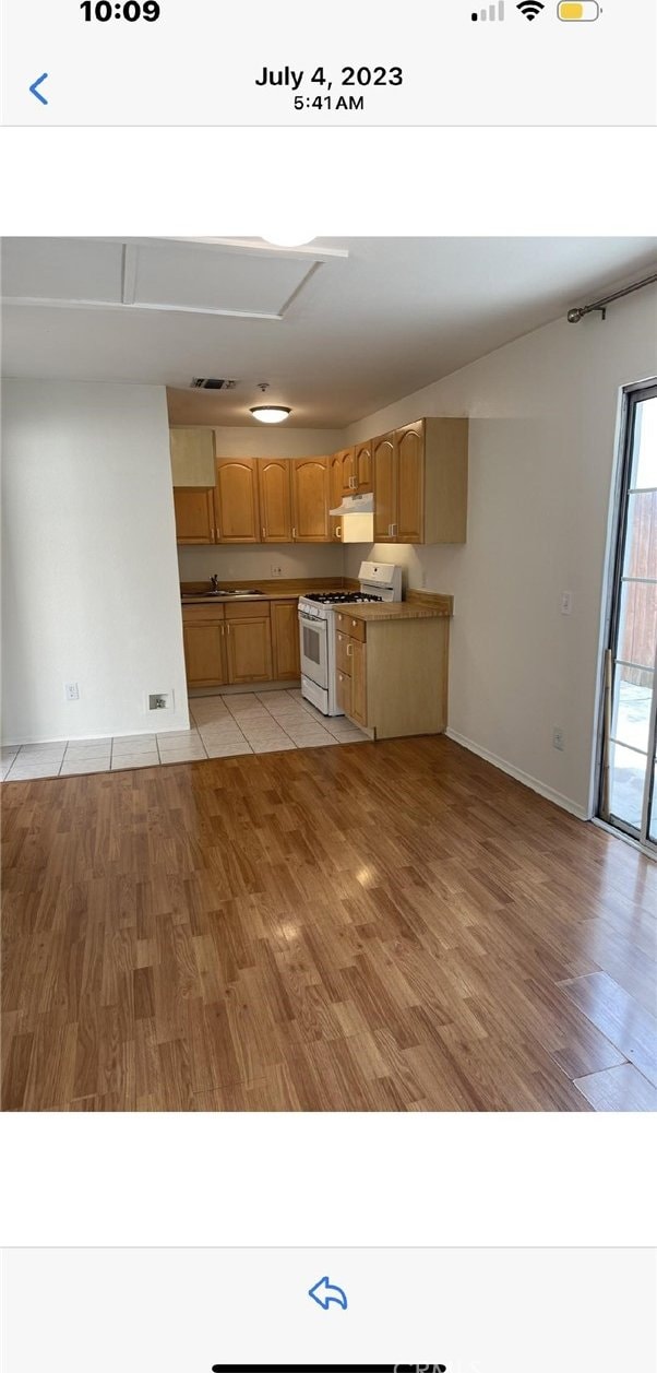 kitchen featuring light wood-type flooring, light brown cabinets, and white gas range oven