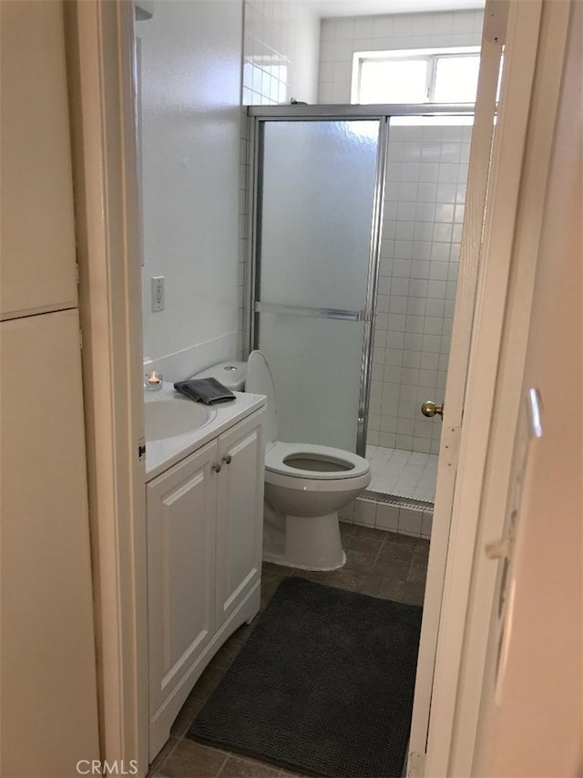 bathroom featuring walk in shower, vanity, tile patterned flooring, and toilet