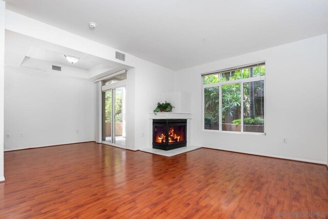 unfurnished living room featuring a raised ceiling and hardwood / wood-style flooring