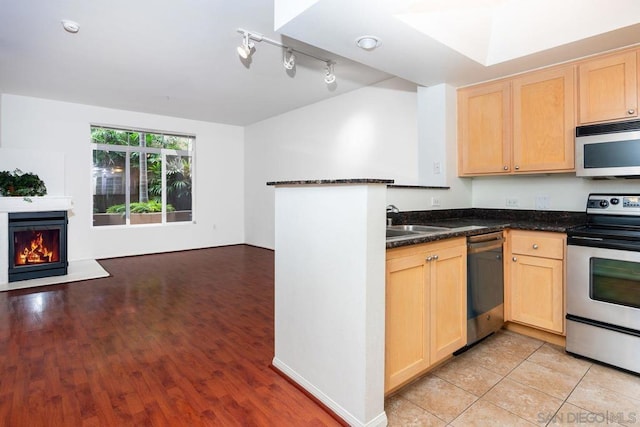 kitchen featuring sink, appliances with stainless steel finishes, track lighting, dark stone counters, and light brown cabinets