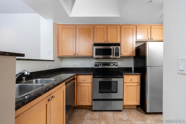 kitchen with appliances with stainless steel finishes, sink, light brown cabinets, and dark stone counters