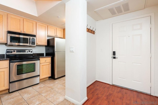 kitchen with stainless steel appliances, light tile patterned floors, and light brown cabinetry