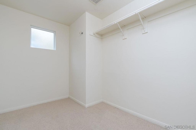 walk in closet featuring light colored carpet