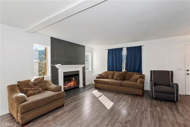 living room with beam ceiling, a large fireplace, and hardwood / wood-style floors