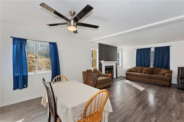 dining area with ceiling fan, wood-type flooring, and a large fireplace