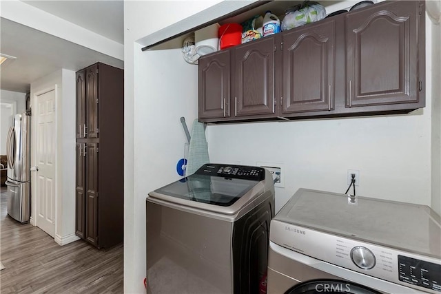 laundry room with cabinets, light hardwood / wood-style flooring, and washing machine and clothes dryer