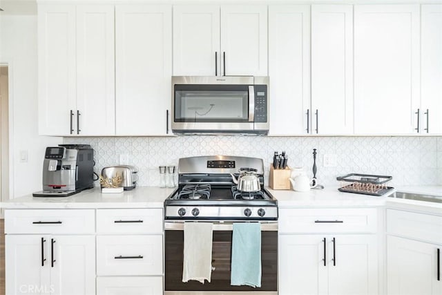 kitchen featuring stainless steel appliances, white cabinetry, and tasteful backsplash