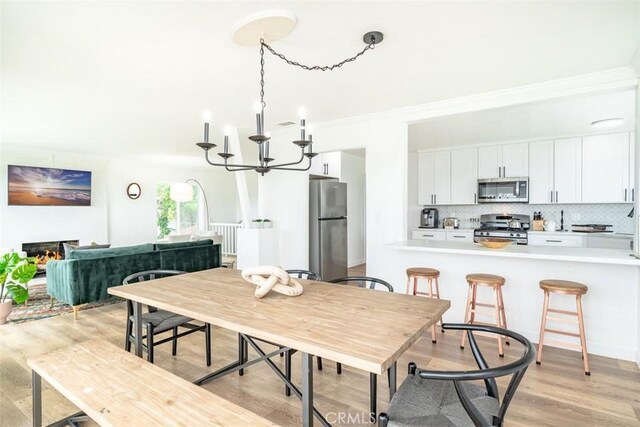 dining room featuring light hardwood / wood-style flooring, crown molding, and an inviting chandelier